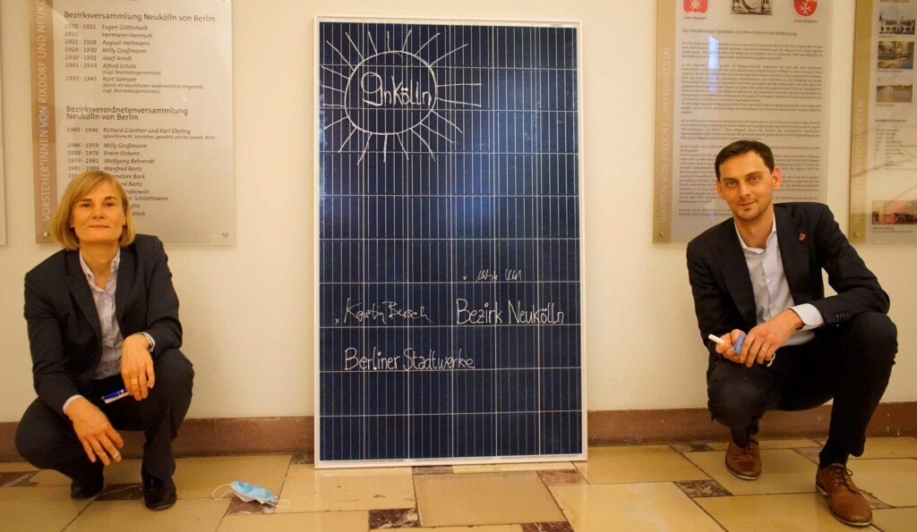 Stadtwerke-Geschäftsführerin Dr. Kerstin Busch und Bezirksbürgermeister Martin Hikel hocken neben einem aufgestellten Solarmodul