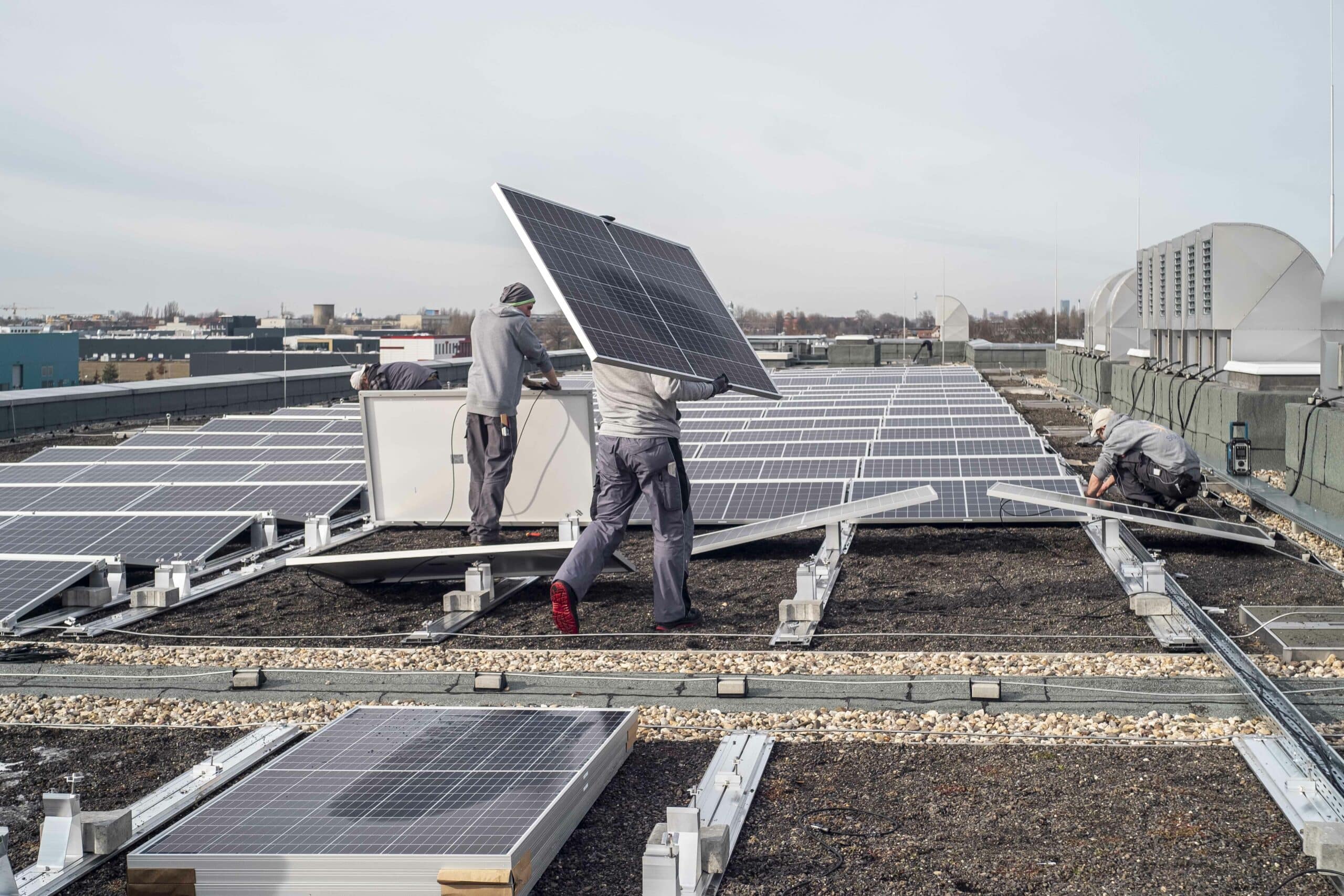 Drei Männer installieren eine Solaranlage auf dem Dach der HU-Speicherbibliothek.
