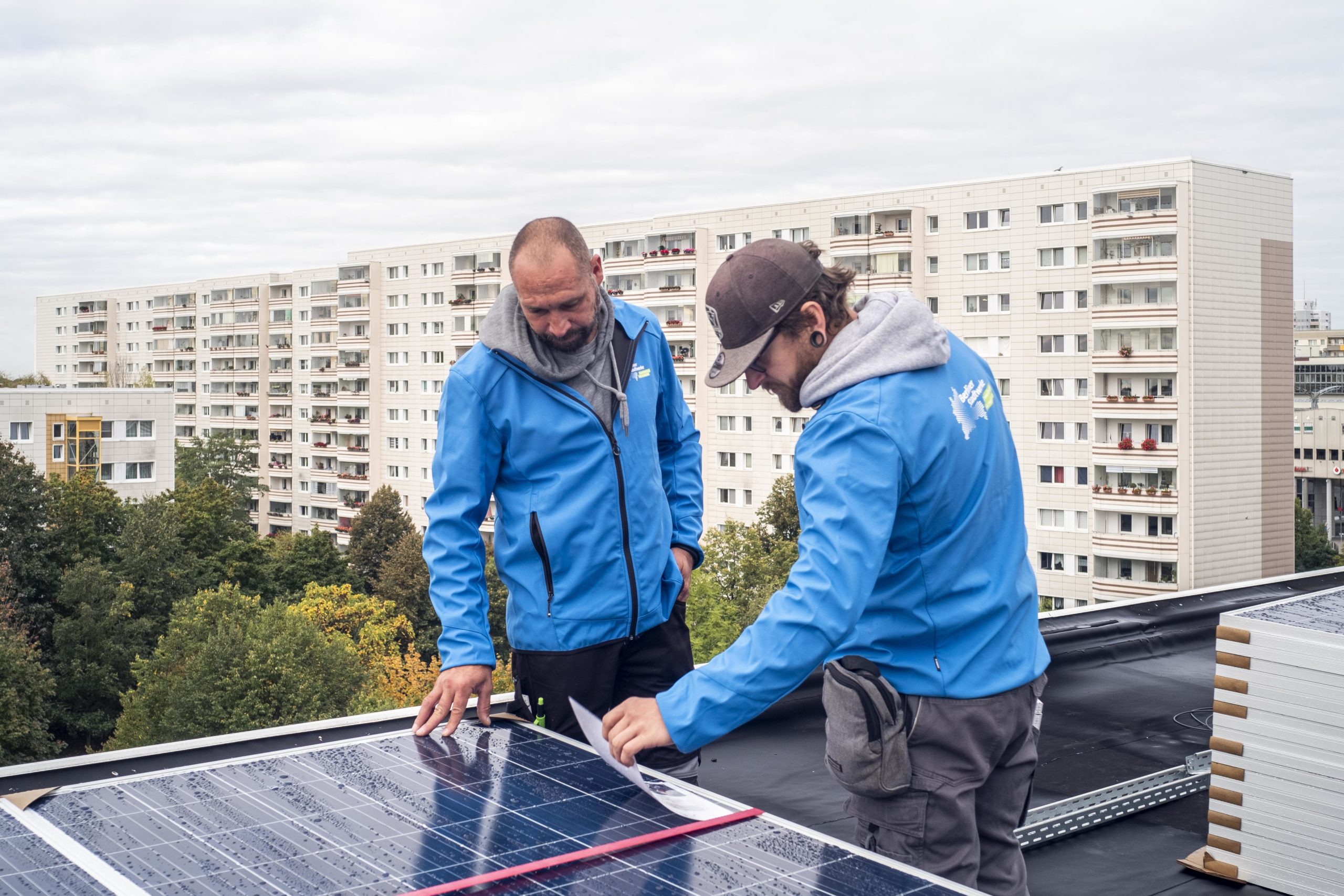 Zwei Stadtwerke-Mitarbeiter stehen vor einem Solarmodul
