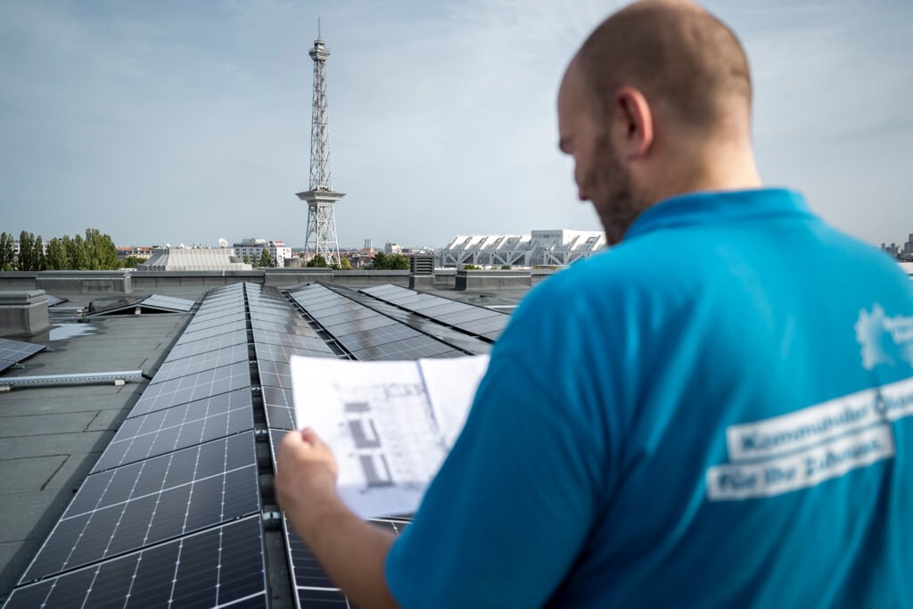 Projektleiter der Berliner Stadtwerke auf einem Hallendach der Messe Berlin mit Solaranlage