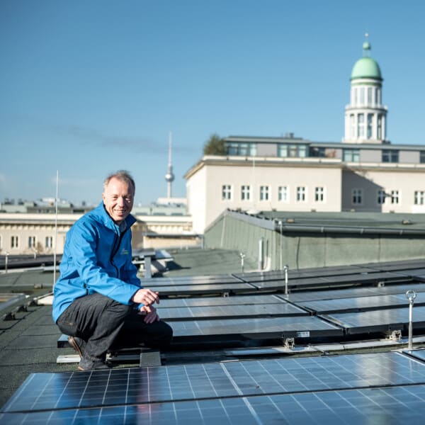 Ein Mitarbeiter der Berliner Stadtwerke hockt auf dem Dach des Georg-Friedrich-Händel-Gymnasiums neben der Solaranlage