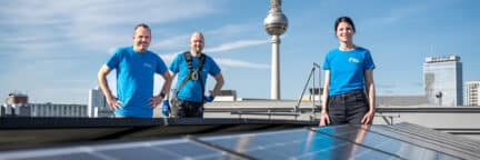 Mitarbeiter:innen der Berliner Stadtwerke auf einem Solardach vor dem Berliner Fernsehturm